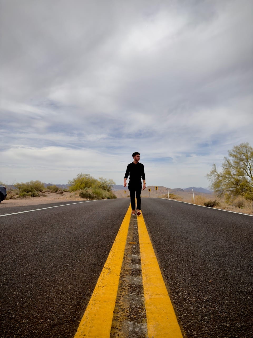 Marcus Miller standing on the centerline of a desert road.